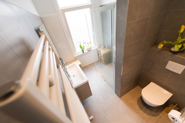 Bovenaanzicht van de badkamer met nieuw toilet, douchecabine en designradiator.